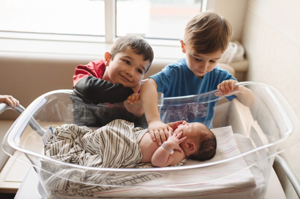 big brothers meeting baby brother for the first time