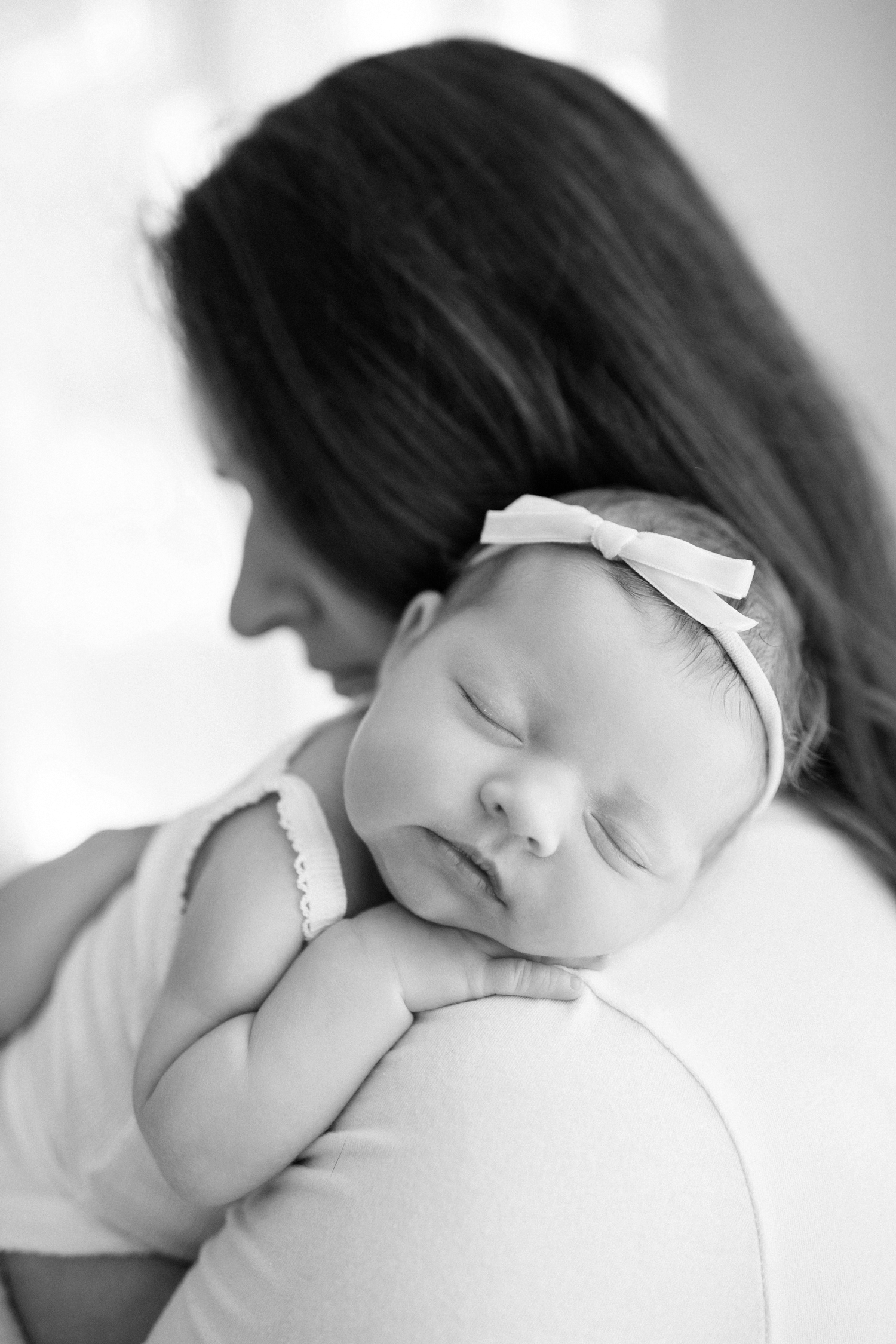 Black and white newborn baby girl over mom's shoulder.