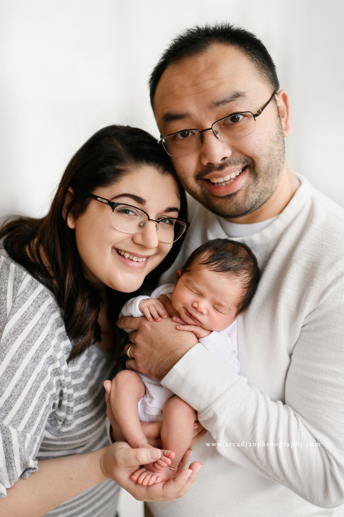 Newborn pose with mom and dad - learn more about booking newborn photos.