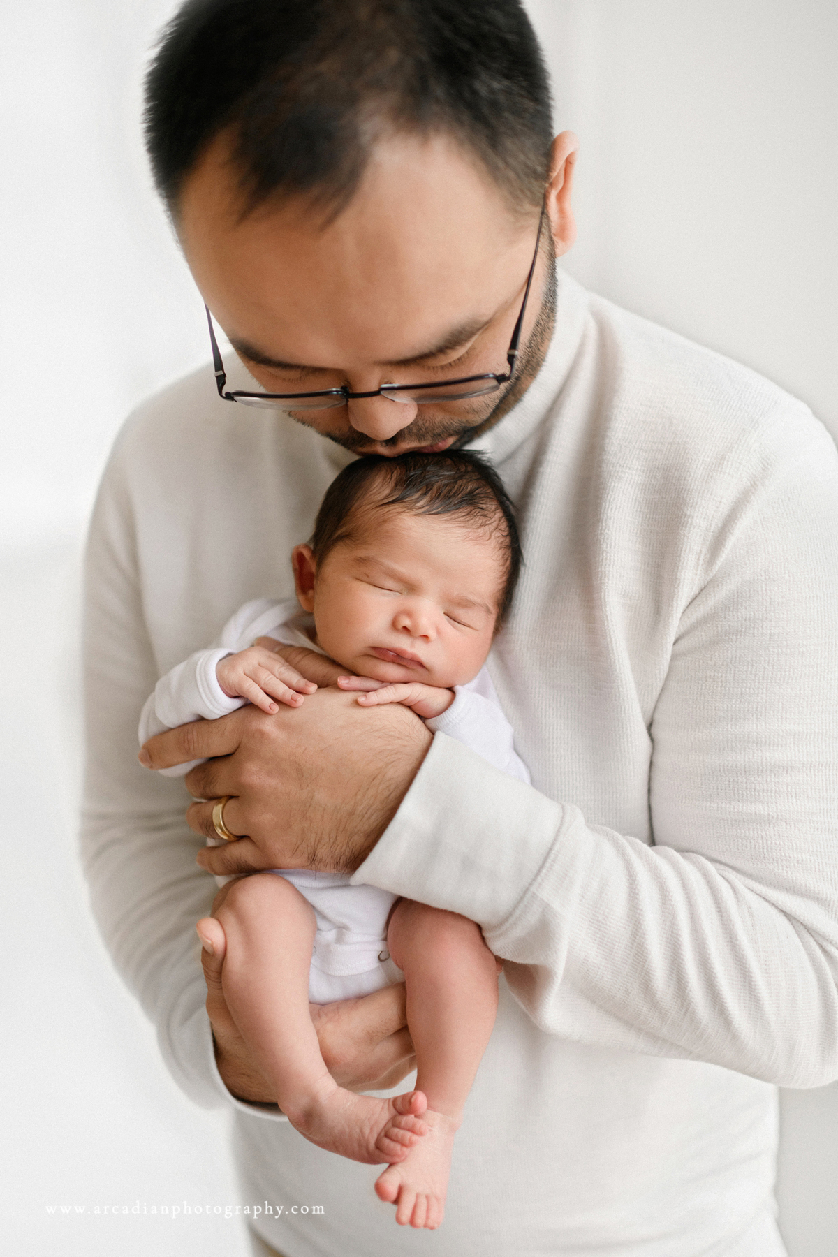 Dad kissing newborn - learn more about booking newborn photos.