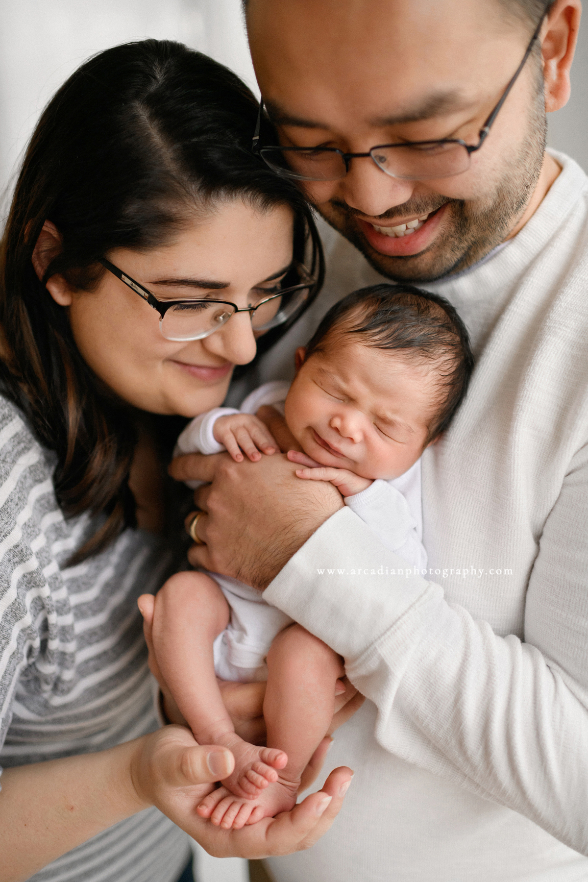 Newborn pose with mom and dad - learn more about booking newborn photos.
