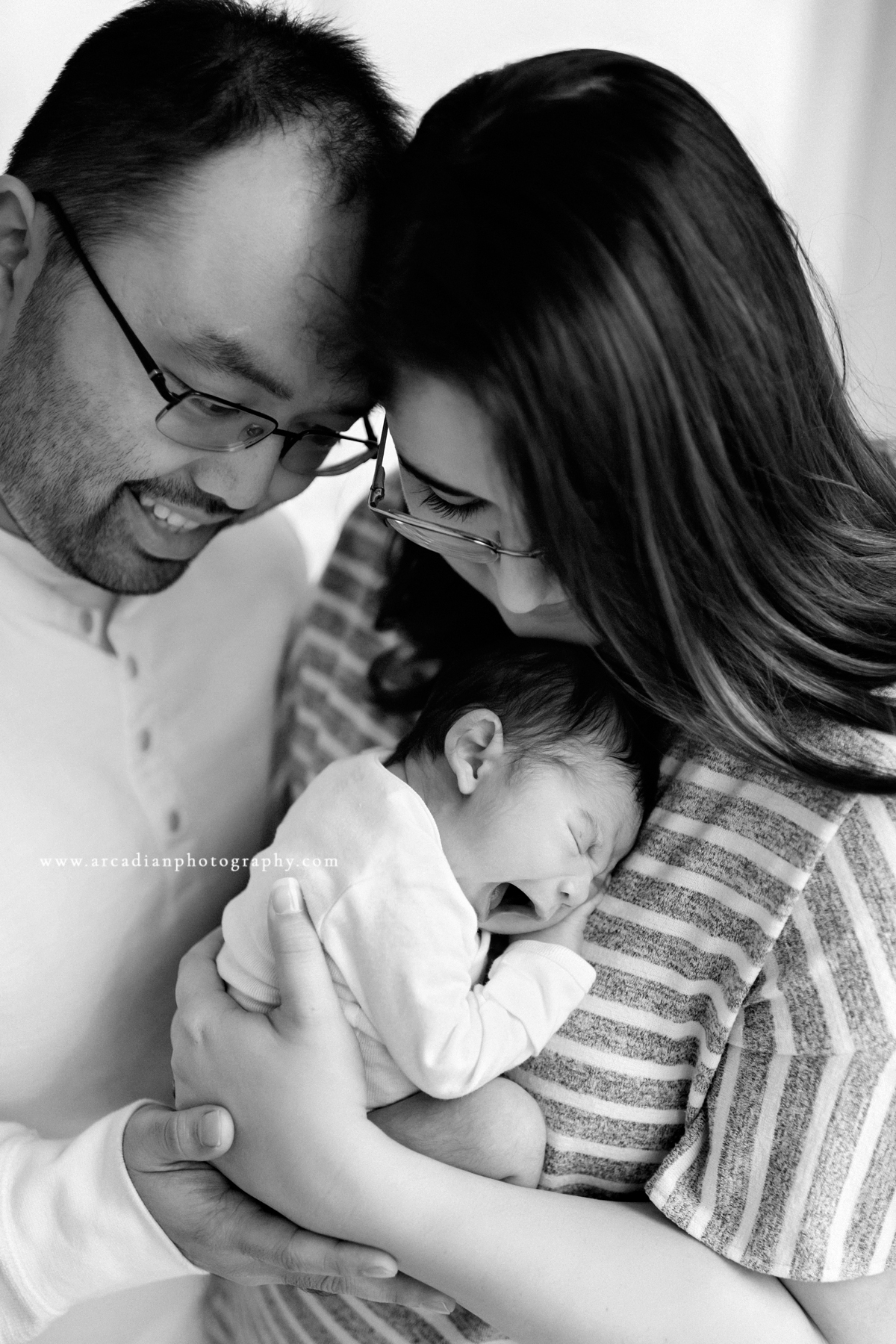 Snuggled with mom and dad - learn more about booking newborn photos.