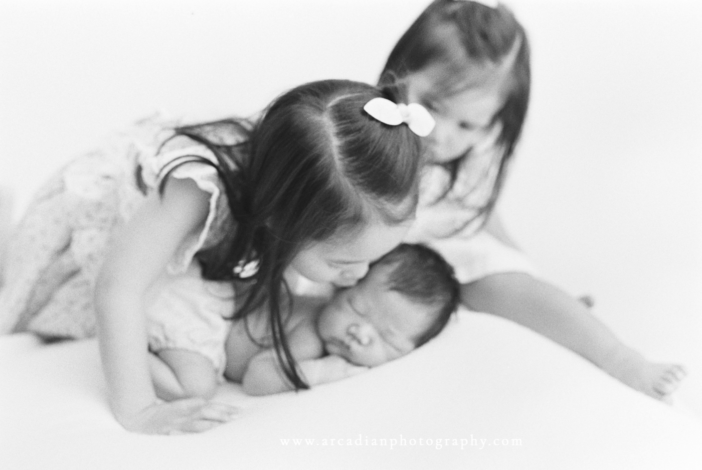 Older sister kissing newborn baby brother - Arcadian Photography