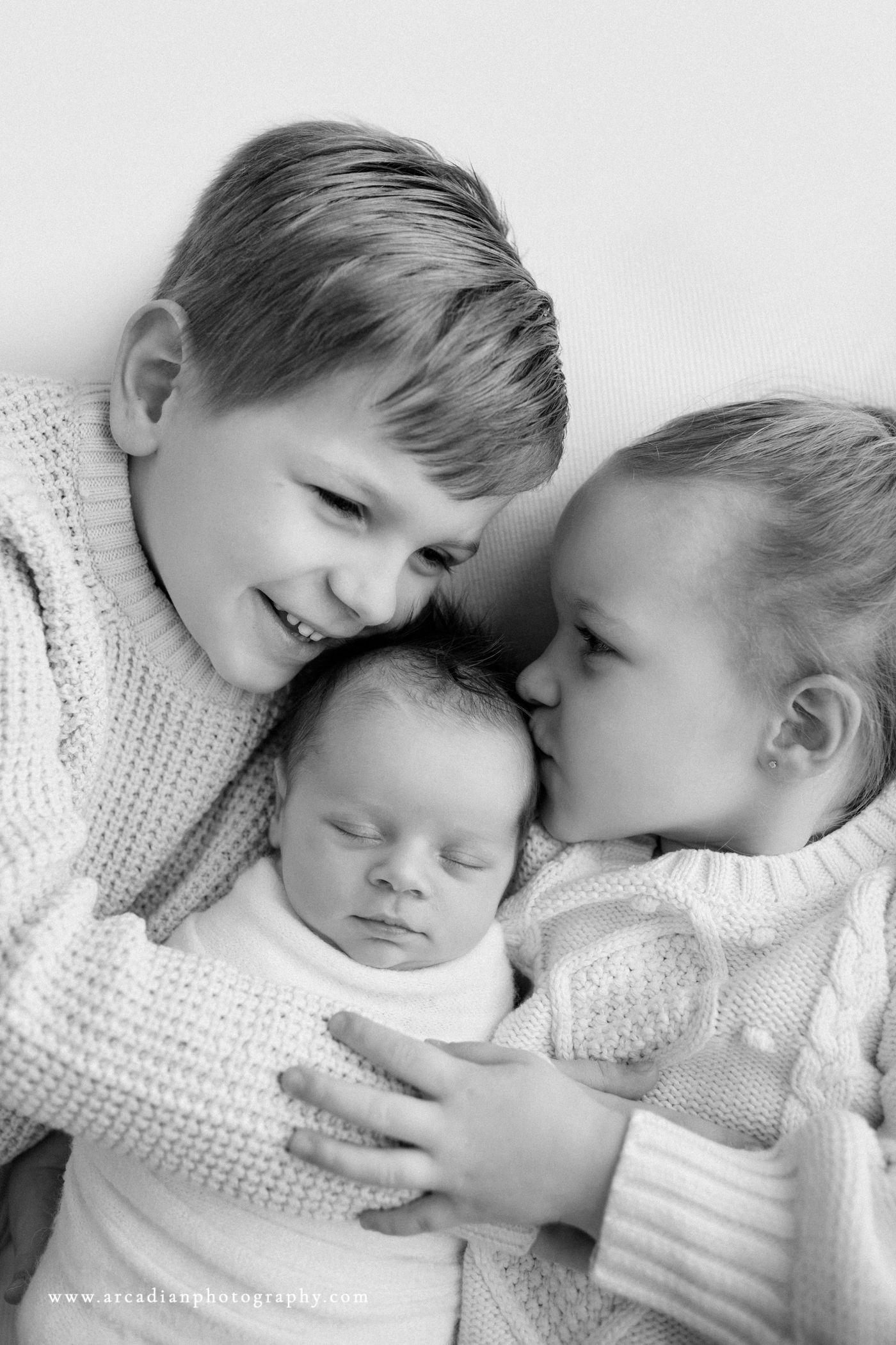 older brother and sister with newborn baby brother