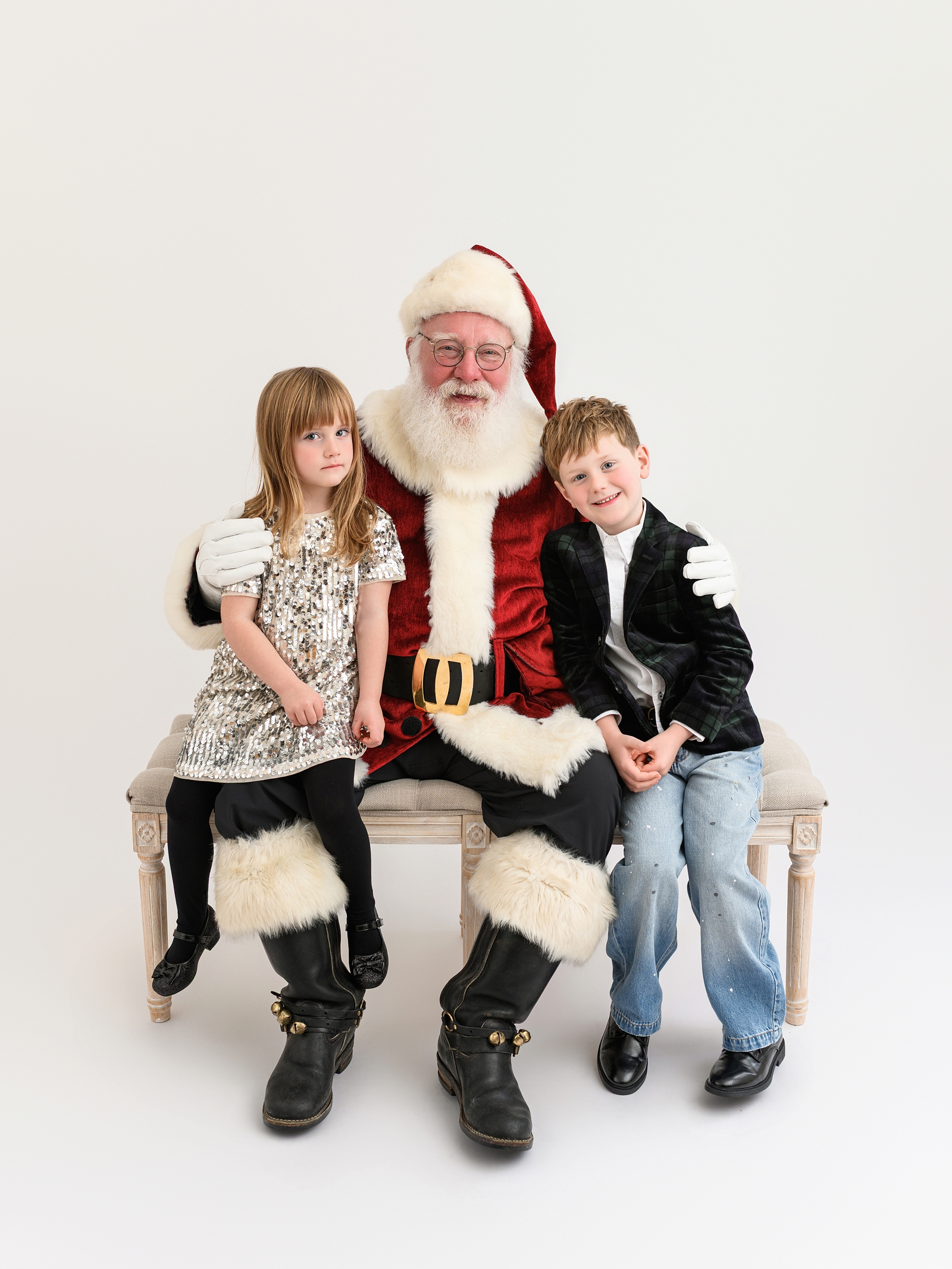 Children wearing festive holiday outfits with subtle sparkle for Santa photos.